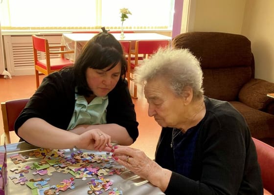 Resident and staff member working on a puzzle together