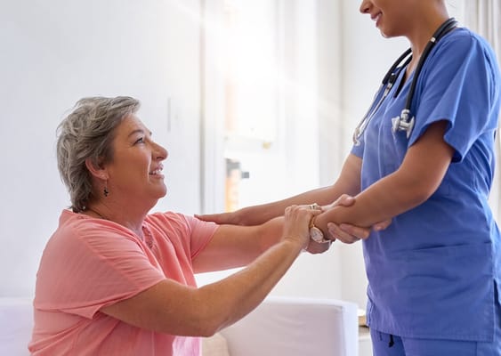 A nurse assisting a smiling resident in a bright indoor setting
