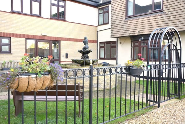 A garden fountain surrounded by flowers and benches
