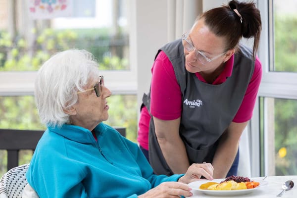Staff serving food to a resident in a dining area