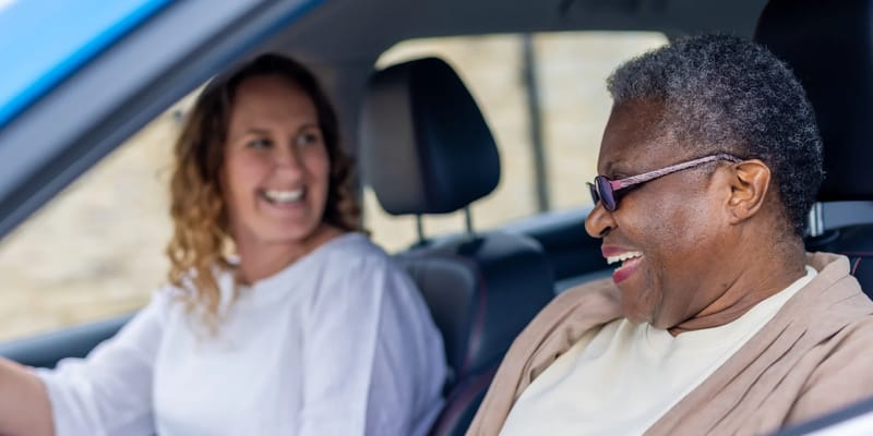 Two women laughing inside a vehicle