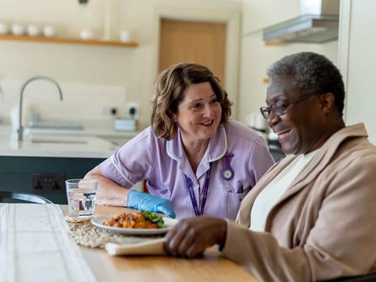 Caregiver serving food to a smiling resident