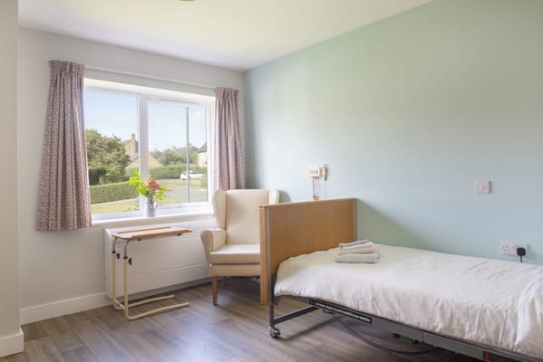 A private room in a senior care facility with a bed and a chair.