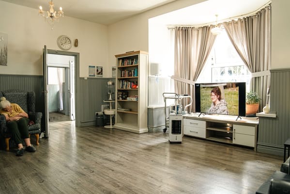 Common area with a resident and a TV displaying a woman outdoors