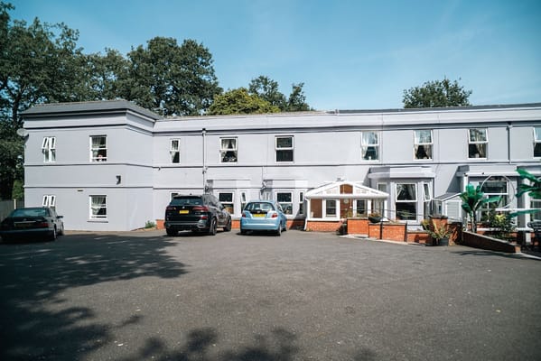 Exterior view of Forest Lodge Care Home and parking area