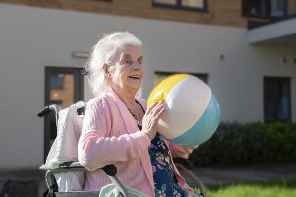 Resident in a wheelchair enjoying a beach ball outside