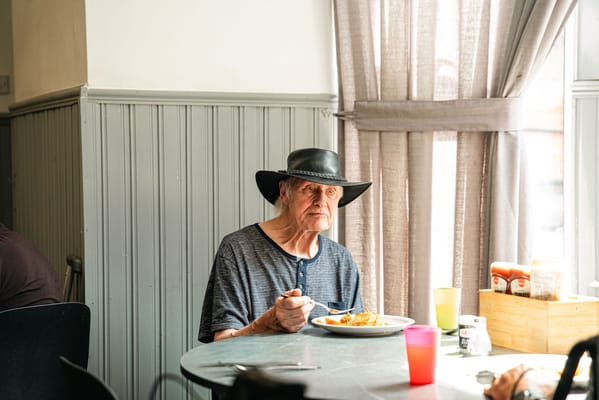 An elderly man enjoying a meal in a dining area