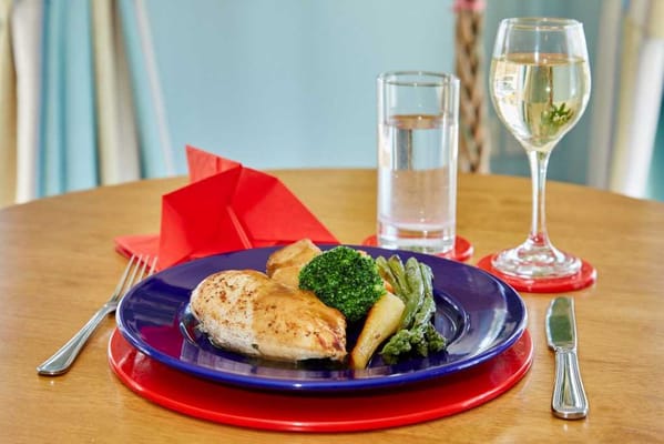A plated meal with chicken, vegetables, and a drink