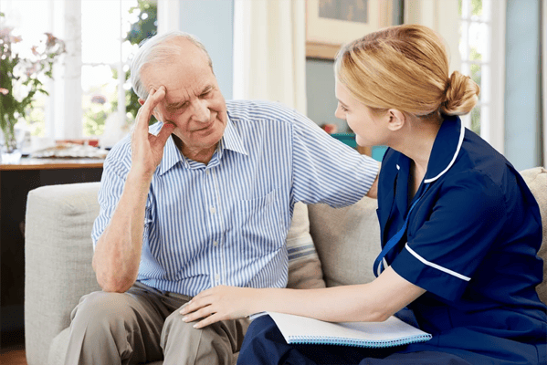 Staff member assisting a senior resident in a warm setting