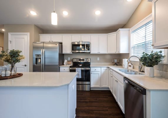 A bright, modern kitchen with white cabinets and stainless steel appliances