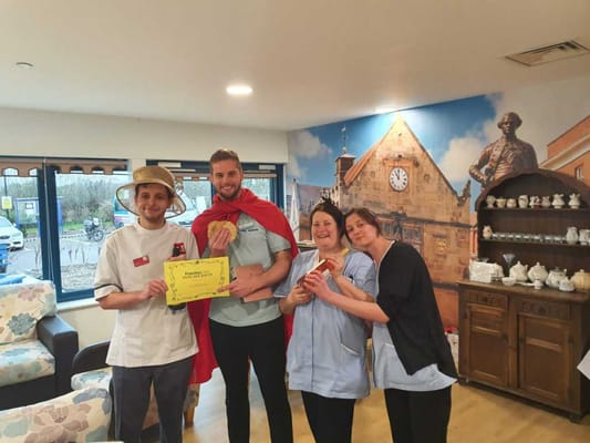 Staff celebrating with certificate in a cozy common area