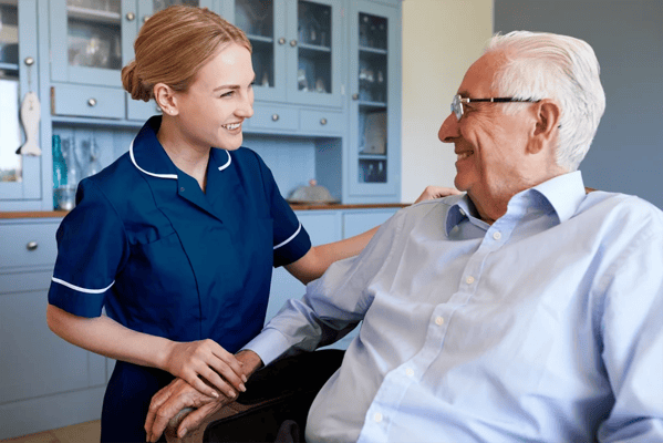 Caregiver assisting an elderly man in a living area