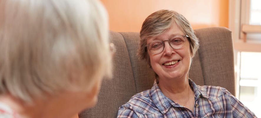 Two smiling residents chatting in a cozy common area