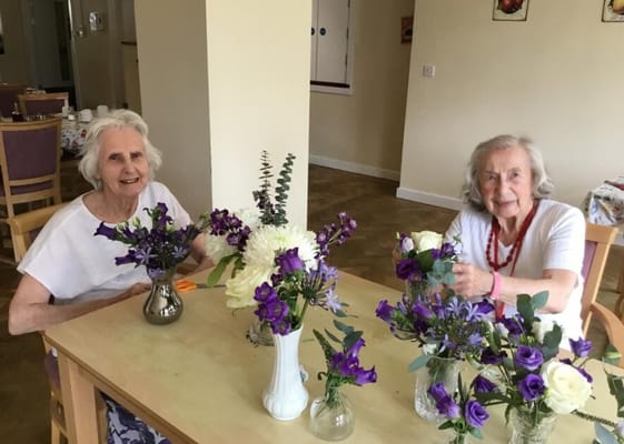Two residents arranging flowers at a table