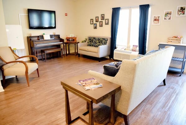 Bright communal area with seating and a piano