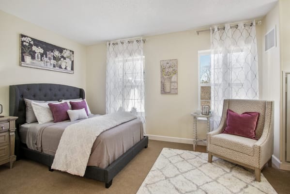 A cozy resident room with a bed, armchair, and decor