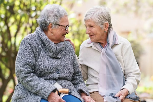 Two elderly women enjoying a conversation outdoors
