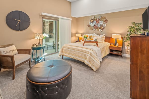 Well-decorated private resident room with a bed and seating