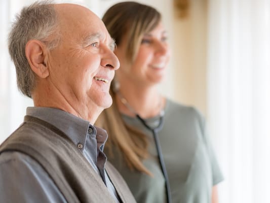 A resident smiling with a staff member in a bright room