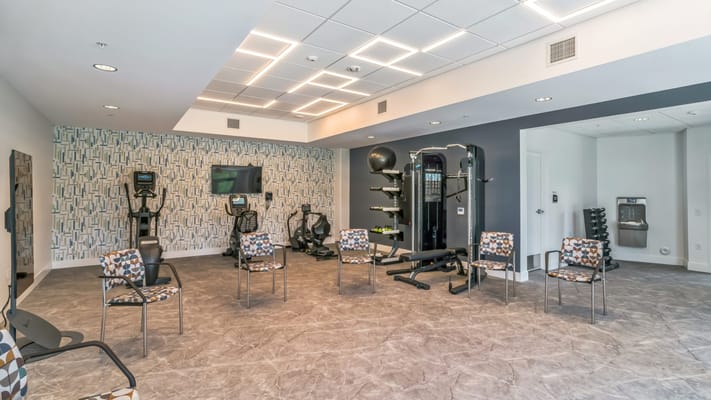 Interior fitness area with workout equipment and chairs