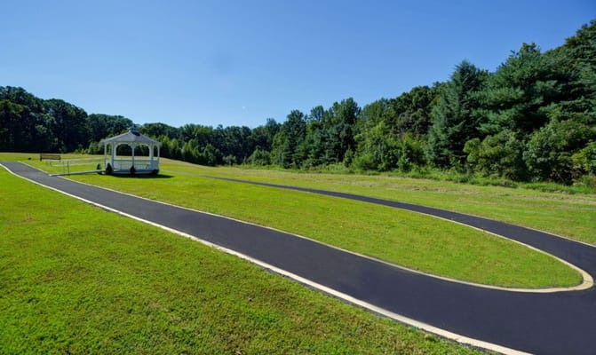 A walking path with a gazebo in a green outdoor space