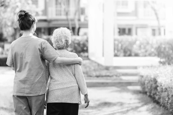 A caregiver walking with a resident in a garden