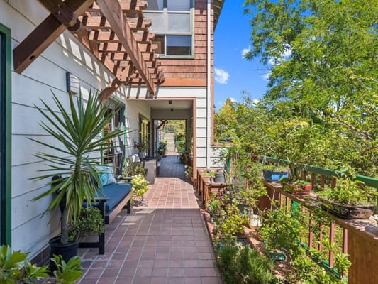 A sunny outdoor walkway with plants and seating