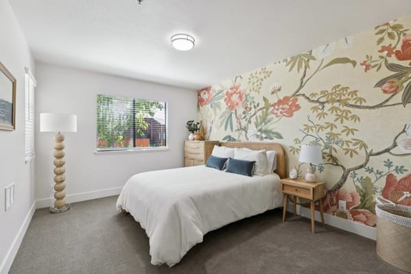 Cozy resident room with floral wallpaper and queen bed