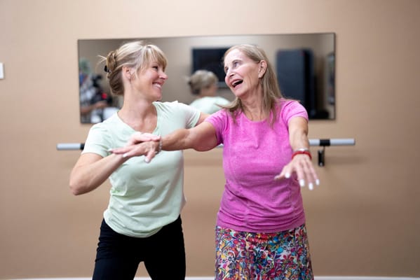 Two women enjoying a joyful dance class in a fitness room