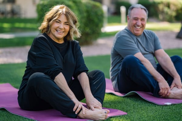 Two residents stretching outdoors on yoga mats
