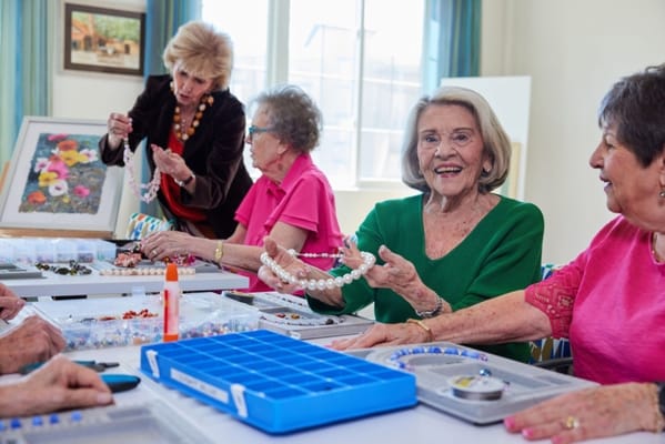Residents engaged in a beading activity at a table