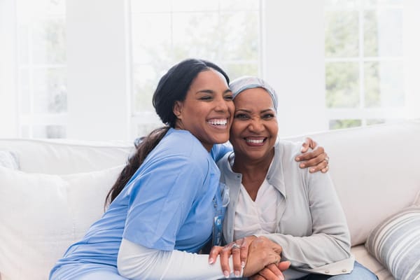 Caregiver and resident smiling together in a bright common area