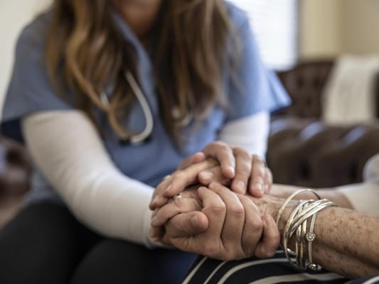 Caregiver holding a resident's hands in a shared moment