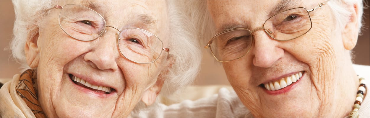 Two smiling elderly women with glasses