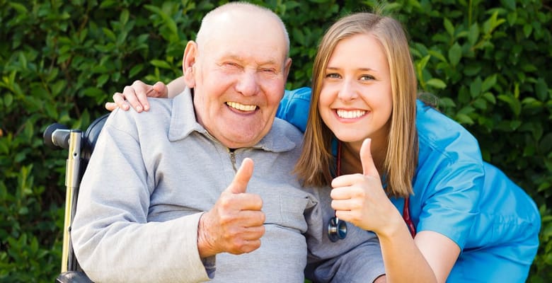 Resident and staff member giving thumbs up outdoors