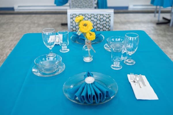 Dining table set up with yellow flowers and glassware