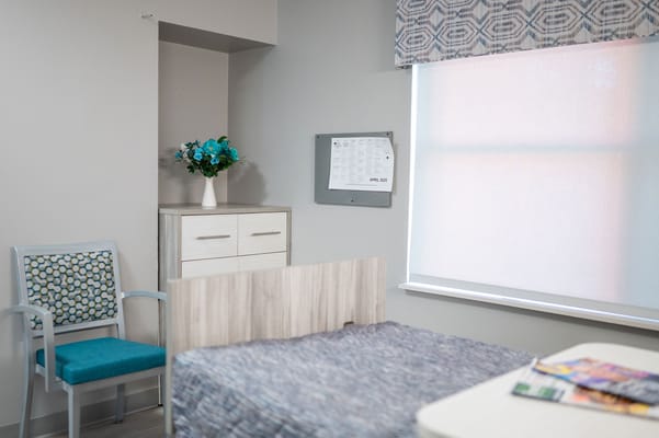 A well-furnished resident room with a bed and a floral arrangement