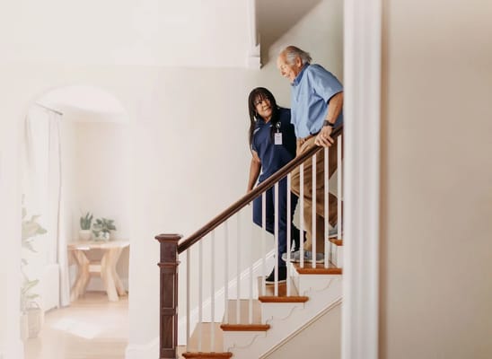 A staff member assisting a resident down the stairs