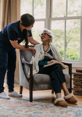 Care staff assisting a resident in a cozy sitting area