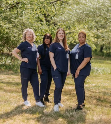 Four staff members in scrubs posing outside