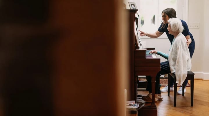 A caregiver assisting a resident at the piano