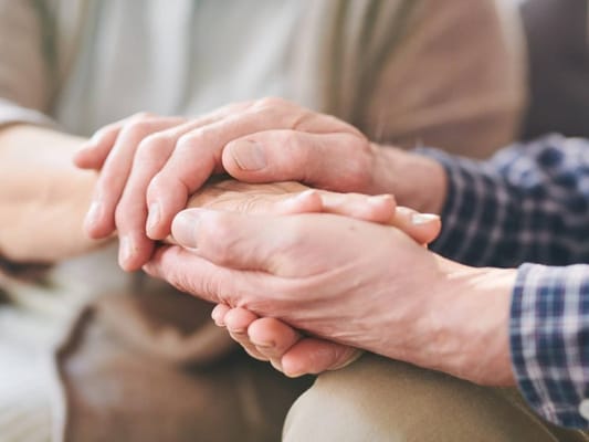 Two hands gently clasped together in a caring gesture