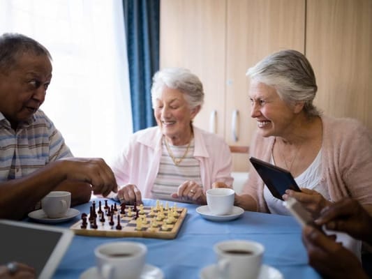 Seniors playing chess and enjoying coffee in a common area