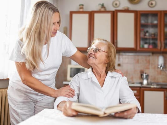 Caregiver and resident sharing a moment in a bright kitchen