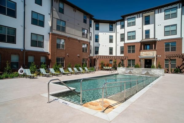 Outdoor pool area with lounge chairs and building facade