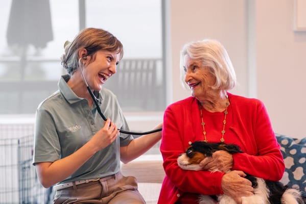 A caregiver interacting with a resident and a dog