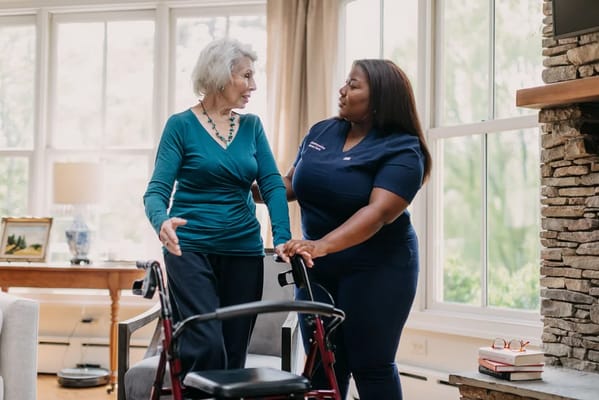 Staff assisting a resident indoors with a walker
