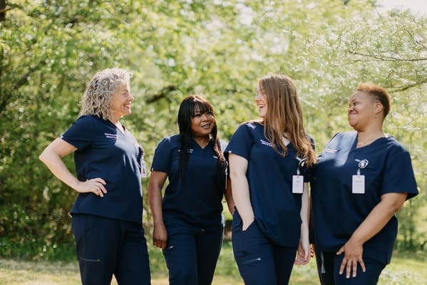 Four staff members smiling outdoors in scrubs