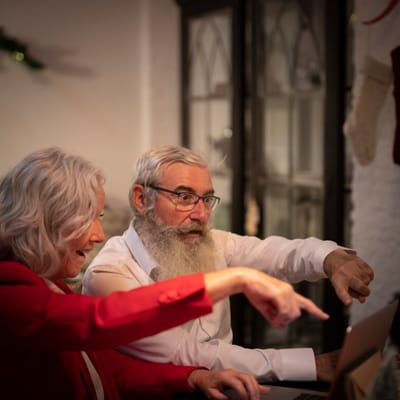 Two seniors engaged in conversation over a laptop