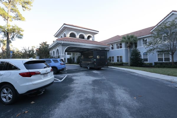 View of the entrance with parked cars and a delivery truck